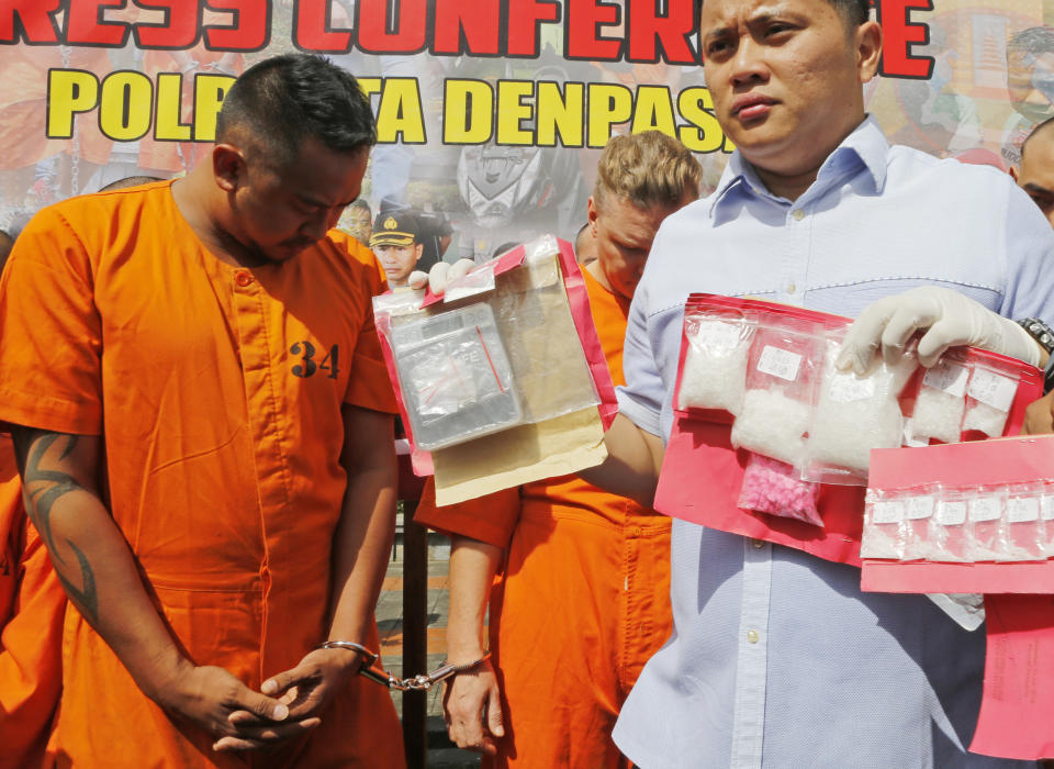 Police officers show evidence as they parade Australian nationals David van Iersel, rear right, and William Cabantog, left, during a press conference at the regional police headquarters in Denpasar, Bali, Indonesia Tuesday, July 23, 2019. Indonesian police say two Australian men have been arrested with cocaine on Bali. (AP Photo/Firdia Lisnawati)