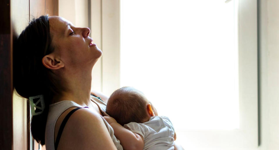 Postpartum psychosis affects around one in 500 mothers after birth. Mother holding baby looking upset. (Getty Images)