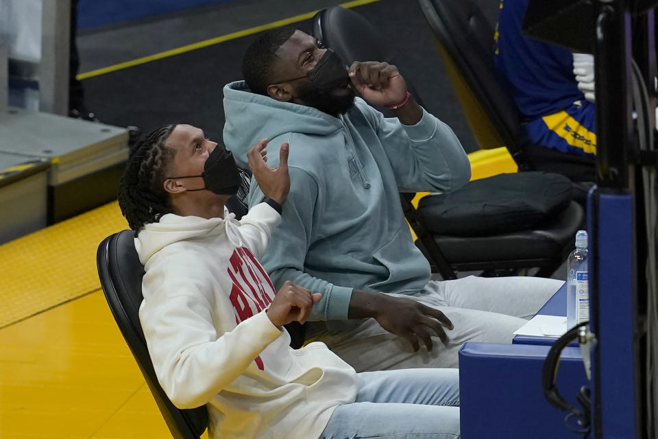 Golden State Warriors' Damion Lee, left, who is sidelined after contracting COVID-19 despite being vaccinated, sits on the sideline with injured Eric Paschall during the second half of an NBA basketball game against the Utah Jazz in San Francisco, Monday, May 10, 2021. (AP Photo/Jeff Chiu)