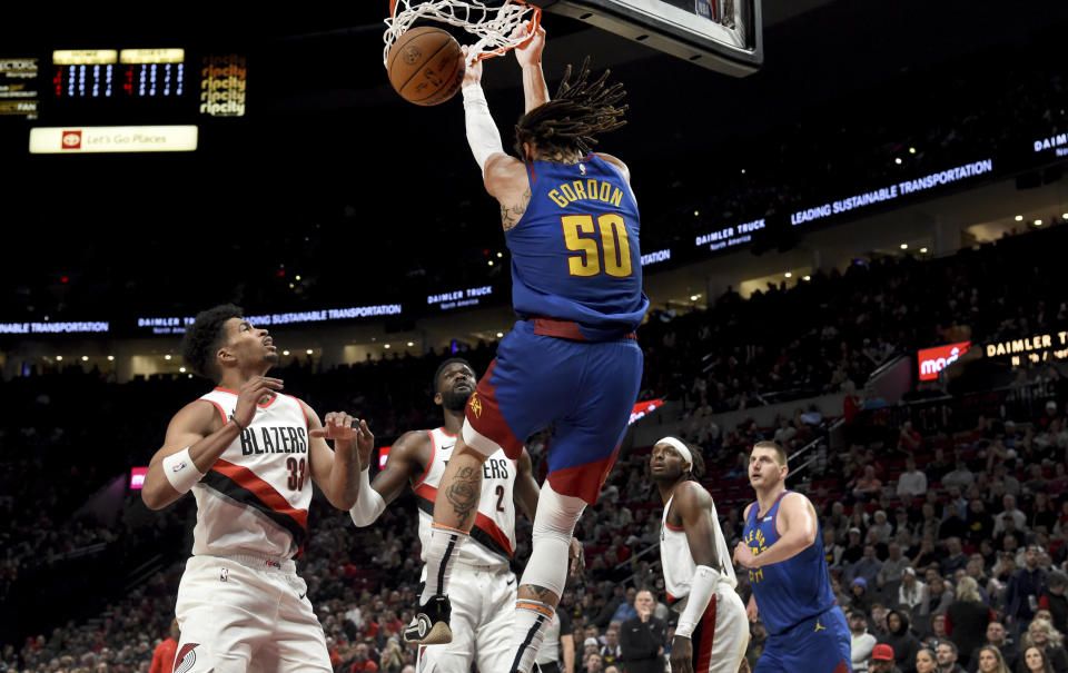 Denver Nuggets forward Aaron Gordon (50) does a reverse dunk as Portland Trail Blazers forward Toumani Camara, left, center Deandre Ayton, second from left, forward Jerami Grant, second from right, and Nuggets center Nikola Jokic, right, watch during the first half of an NBA basketball game in Portland, Ore., Friday Feb. 23, 2024. (AP Photo/Steve Dykes)