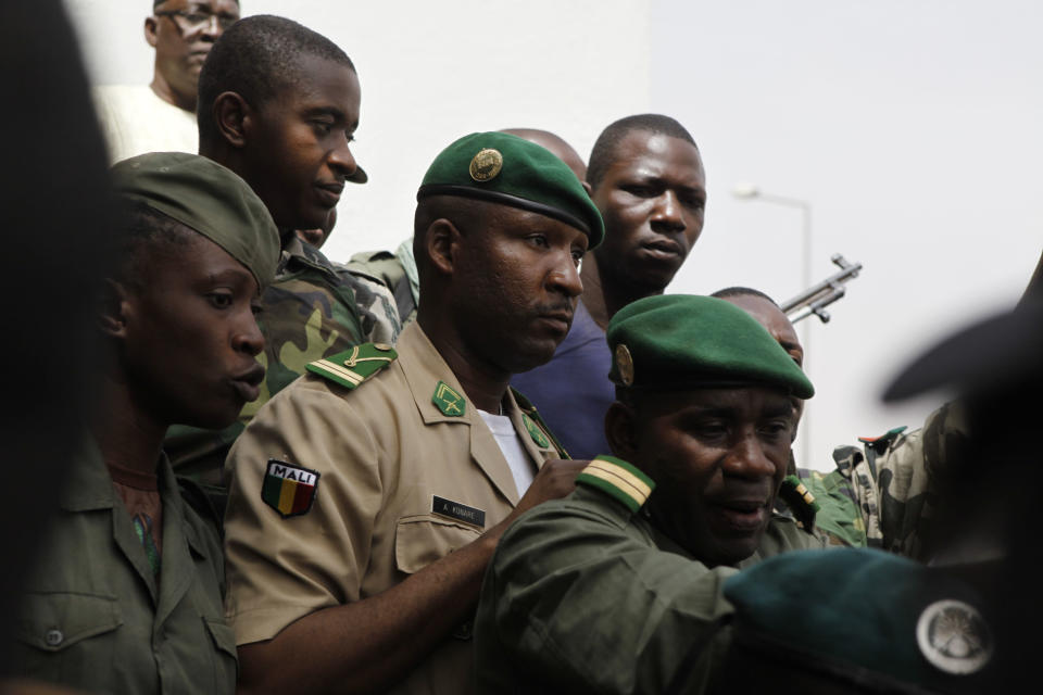 Coup leader Amadou Haya Sanogo, center, is surrounded by security as he arrives to address supporters, as thousands rallied in a show of support for the recent military coup, in Bamako, Mali Wednesday, March 28, 2012. The body representing nations in western Africa has suspended Mali and has put a peacekeeping force on standby in the most direct threat yet to the junta that seized control of this nation in a coup last week. (AP Photo/Rebecca Blackwell)