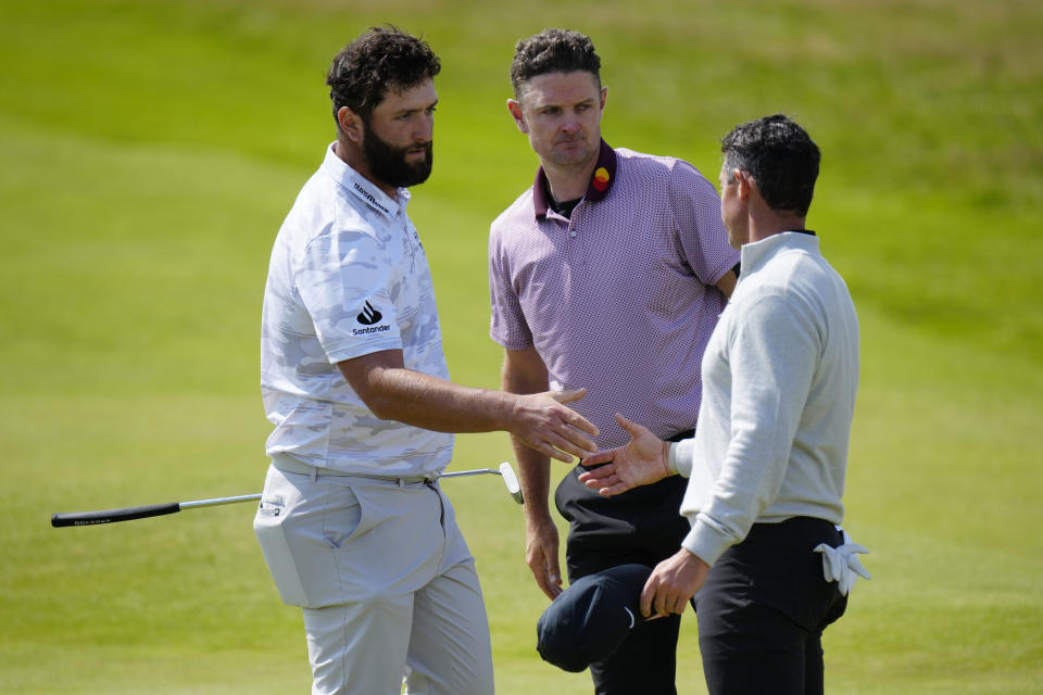 Spain's Jon Rahm, left shakes hands with Northern Ireland's Rory McIlroy, right as England's Justin Rose looks on after they completed their round on the 18th green during the second day of the British Open Golf Championships at the Royal Liverpool Golf Club in Hoylake, England, Friday, July 21, 2023. (AP Photo/Jon Super)