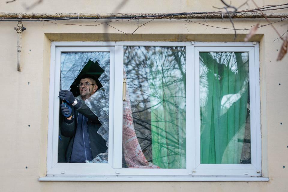 Local resident removes the broken glass from his window damaged by a Russian missile strike (REUTERS)