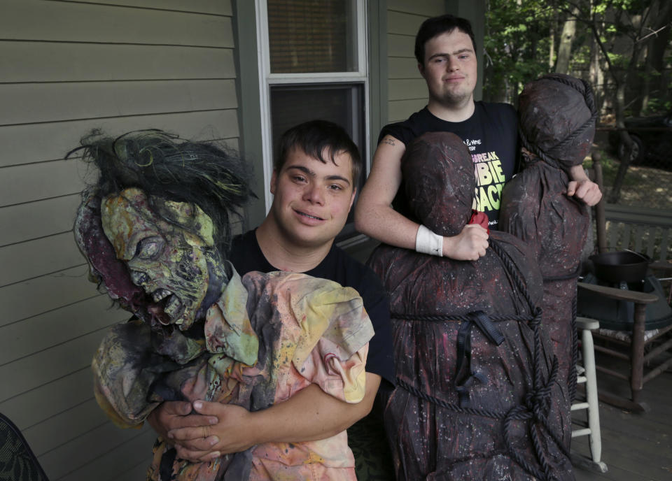 FILE — In this July 12, 2016, file photo, Sam Suchmann, right, and Mattie Zufelt pose with ghoulish figures at Sam's home in Providence, R.I. The two young men with Down syndrome who caused a sensation four years ago when they created their own gory zombie movie are back, this time in a documentary championed by a Hollywood luminary that chronicles their tenacious, years-long effort to see their silver screen dream come to fruition. "Sam & Mattie Make a Zombie Movie," was released Tuesday, April 6, 2021, on Apple TV. (AP Photo/Elise Amendola, File)