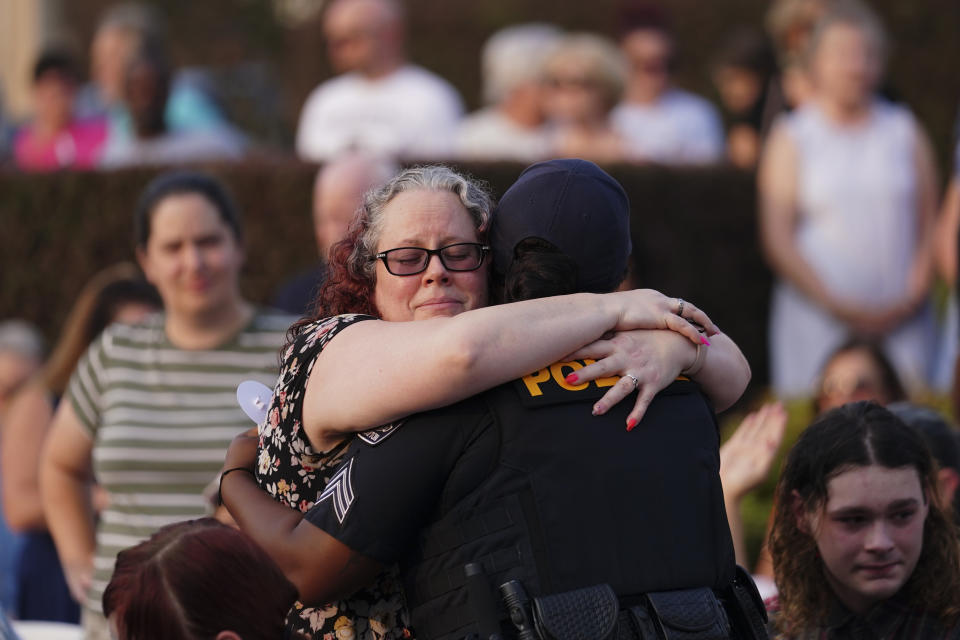 A woman hugs a police officer during a vigil for the victims of Saturday's mass shooting on Monday, July 17, 2023, in Hampton, Ga. (AP Photo/John Bazemore)