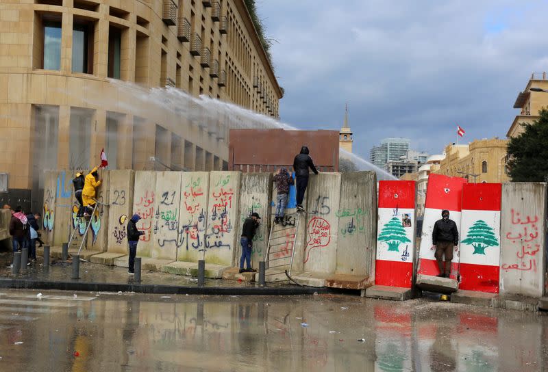 Demonstrators are sprayed with a water cannon during a protest seeking to prevent MPs and government officials from reaching the parliament for a vote of confidence, in Beirut