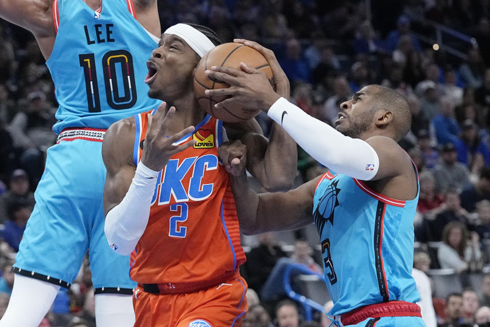 Phoenix Suns guard Chris Paul reaches for the ball controlled by Oklahoma City Thunder guard Shai Gilgeous-Alexander (2) in the first half of an NBA basketball game Sunday, March 19, 2023, in Oklahoma City. (AP Photo/Sue Ogrocki)