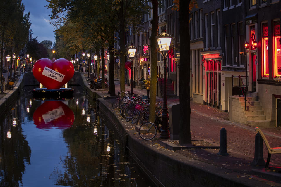 A red heart carries a social distancing message in a near-empty Red Light District in Amsterdam, Netherlands, Friday, Oct. 23, 2020. (AP Photo/Peter Dejong)