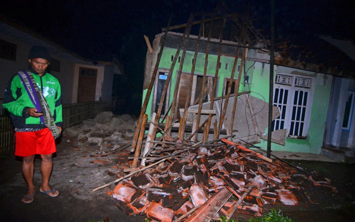 A villager stand near a damaged house - REUTERS