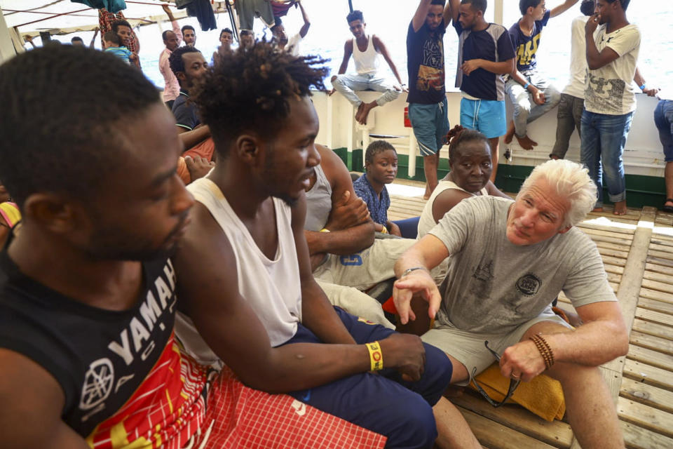 Actor Richard Gere, right, talks with migrants aboard the Open Arms Spanish humanitarian boat as it cruises in the Mediterranean Sea, Friday, Aug. 9, 2019. Open Arms has been carrying 121 migrants for a week in the central Mediterranean awaiting a safe port to dock, after it was denied entry by Italy and Malta. (AP Photo/Valerio Nicolosi)