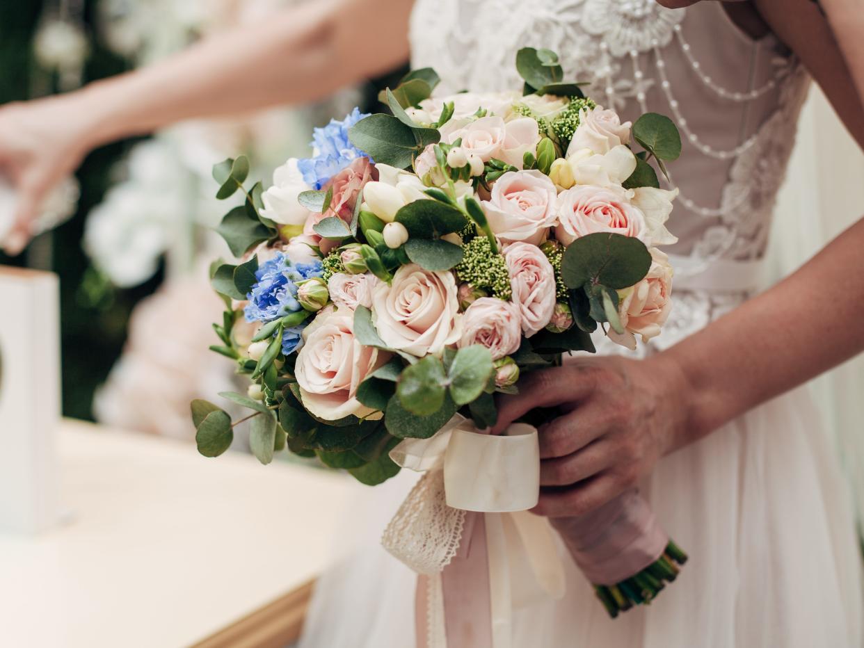 Close up of bride holding bouquet with pink and blue roses
