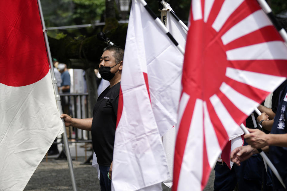 Visitors carry Japanese flags and a rising sun flag at Yasukuni Shrine Monday, Aug. 15, 2022, in Tokyo. Japan marked the 77th anniversary of its World War II defeat Monday. (AP Photo/Eugene Hoshiko)