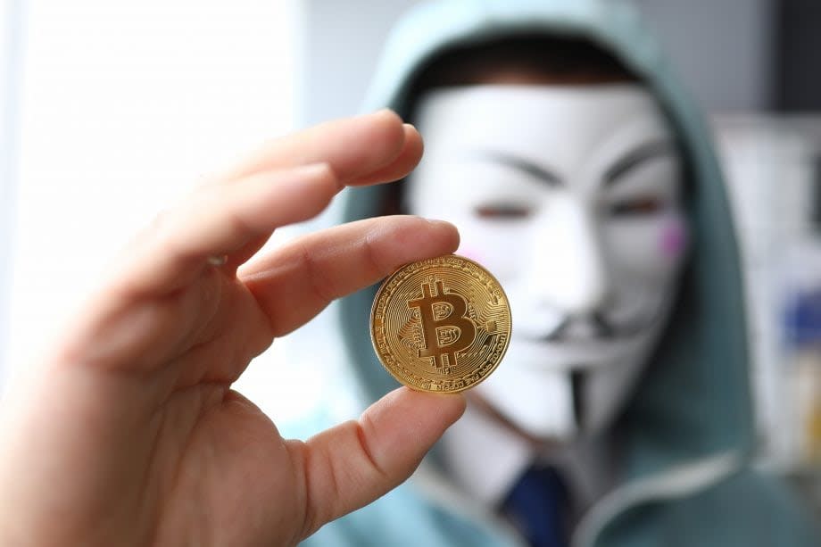 Bitcoin Münze wird von Menschen mit Maske hochgehalten.