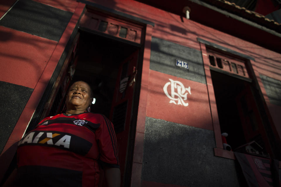 In this April 28, 2014 photo, Maria Boreth de Souza, alias Zica, poses for a portrait in her Flamengo club jersey in the doorway of her home painted in her team's colors of red and black in the Olaria neighborhood of Rio de Janeiro, Brazil. The 63-year-old is one of the most die-hard and the best known fans of the iconic team who has over the years become an icon in her own right. Her nickname Zica is honor of former Brazilian soccer great Zico. (AP Photo/Leo Correa)
