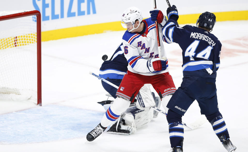 Winnipeg Jets' Josh Morrissey (44) defends against New York Rangers' Jimmy Vesey (26), who attempts to knock the rebound past Jets goaltender Connor Hellebuyck (37) during the second period of an NHL hockey game Friday, Oct. 14, 2022, in Winnipeg, Manitoba. (John Woods/The Canadian Press via AP)