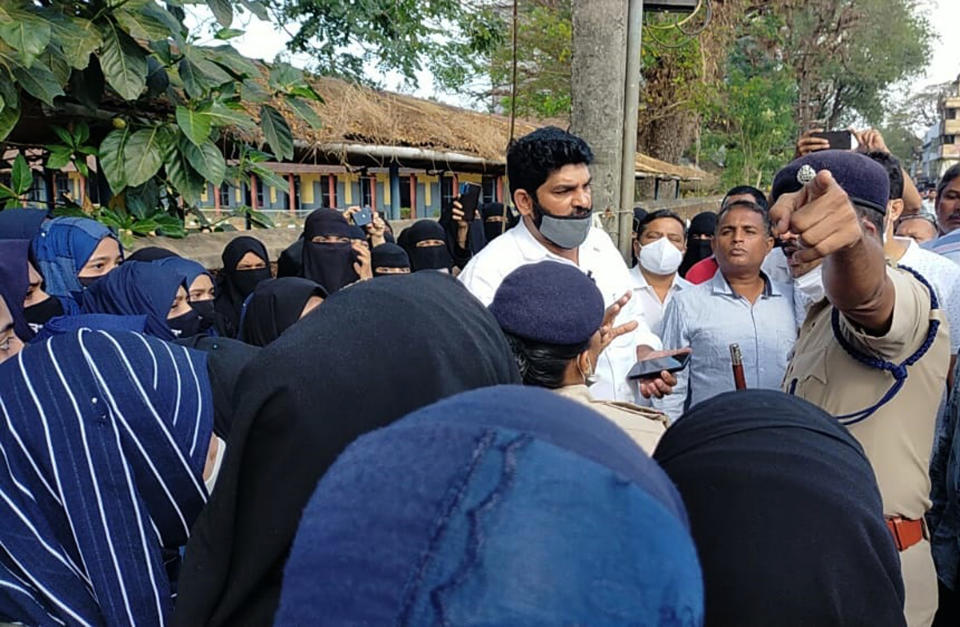 Parents of Indian students who were barred from entering their classrooms for wearing hijab, a headscarf used by Muslim women, argue with a police official outside the college premises in Udupi, India, Friday, Feb. 4, 2022. Muslim girls wearing hijab are being barred from attending classes at some schools in the southern Indian state of Karnataka, triggering weeks of protests by students. (Bangalore News Photos via AP)