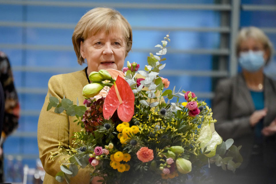 German Chancellor Angela Merkel holds a bouquet from Vice Chancellor and Finance Minister Olaf, Scholz prior to the cabinet meeting at the chancellery in Berlin, Germany, Wednesday, Nov. 24, 2021. Merkel was given flowers as this was probably her last cabinet session as German Chancellor as negotiations are going on to form a new government after elections were held in September. (AP Photo/Markus Schreiber, Pool)