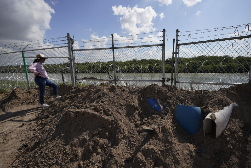 Magali Urbina stands near a gate on pecan farm that has been bulldozed, locked and lined with concertina wire along the Rio Grande, near Eagle Pass, Texas, Monday, July 7, 2023. Texas Republican Gov. Greg Abbott has escalated measures to keep migrants from entering the U.S. He's pushing legal boundaries along the border with Mexico to install razor wire, deploy massive buoys on the Rio Grande and bulldozing border islands in the river. (AP Photo/Eric Gay)