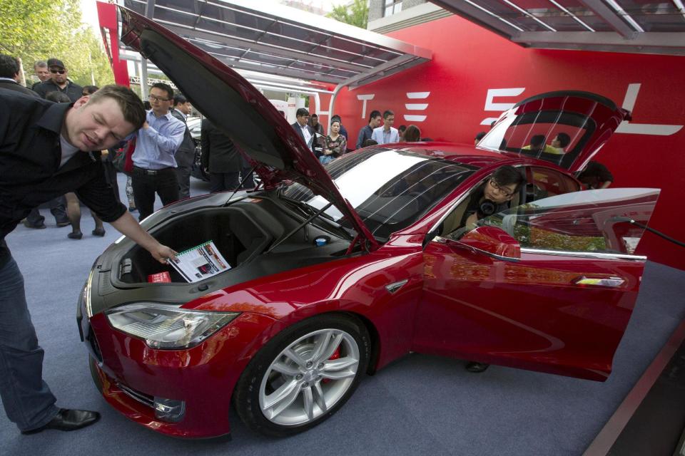 Customers and journalists examine a Tesla Model S sedan at an event in Beijing, China, Tuesday, April 22, 2014. Tesla Motors delivered its first eight electric sedans to customers in China on Tuesday and Musk said the company will build a nationwide network of charging stations and service centers as fast as it can. (AP Photo/Ng Han Guan)