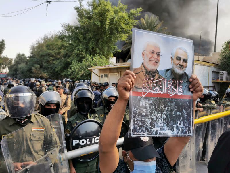 FILE PHOTO: A supporter of Hashid Shaabi (Popular Mobilization Forces) holds a picture of late Iran's Quds Force top commander Qassem Soleimani and Iraqi militia commander Abu Mahdi al-Muhandis who were killed in a U.S. airstrike during a protest in Baghda