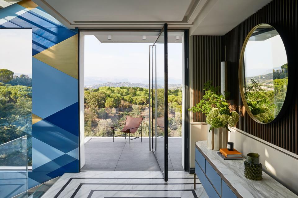 In the stairwell, custom notched rosewood paneling, mirror, sconces, and console table. The ceramic vases are by Floris Wubben. The exterior chair is from Baxter.