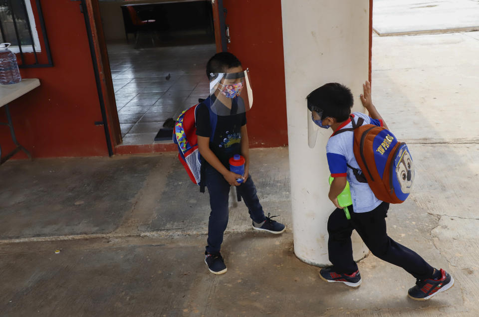 Wearing masks and face shields to curb the spread of the new coronavirus, two students play during the first day of class at the Valentin Gomez Farias Indigenous Primary School in Montebello, Hecelchakan, Campeche state, Monday, April 19, 2021. Campeche is the first state to transition back to the classroom after a year of remote learning due to the pandemic. (AP Photo/Martin Zetina)