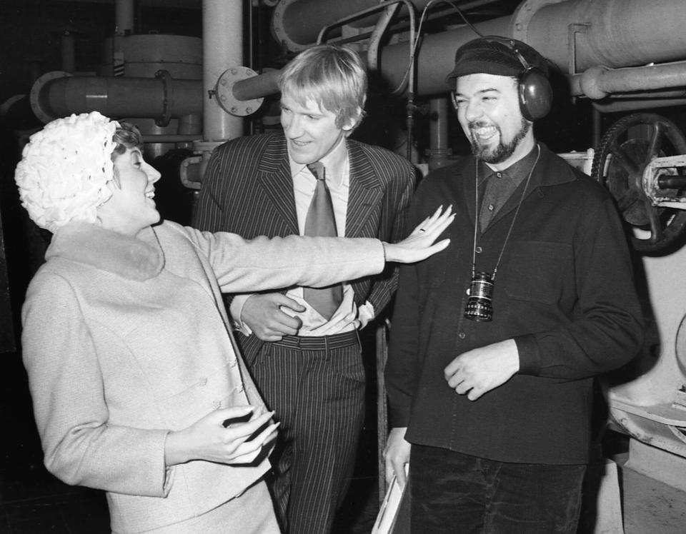 ARCHIVO - La cantante pop Cilla Black y el actor David Warner, en el centro, conversan con el director Peter Hall durante un receso de la filmación de la comedia "Work... Is A Four Letter Word" en Kent, Inglaterra, el 16 de febrero de 1967. Warner, un versátil actor británico cuyos papeles abarcaron desde tragedias de Shakespeare hasta clásicos de culto de ciencia ficción, falleció el domingo 24 de julio de 2022. Tenía 80 años. (Foto AP, archivo)