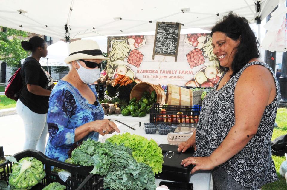 Gabriella Barbosa, right, owner of Barbosa Family Farm, helps customer Maria Gomes during opening day of the Brockton Farmers Market at City Hall Plaza on Friday, July 16, 2021. The market is open Fridays through Oct. 29 and for some extra summer fun features children's entertainment from 11 a.m. to noon through the end of August.