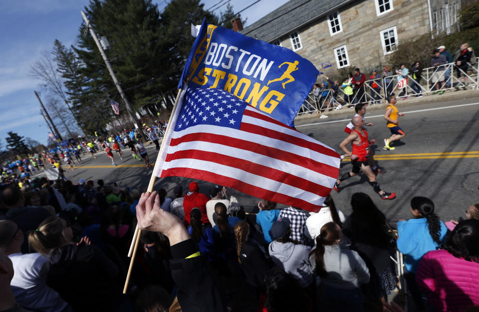 A race fan waves the American flag and a banner bearing the slogan "Boston Strong" as runners compete in the 118th Boston Marathon Monday, April 21, 2014 in Hopkinton, Mass. (AP Photo/Michael Dwyer)