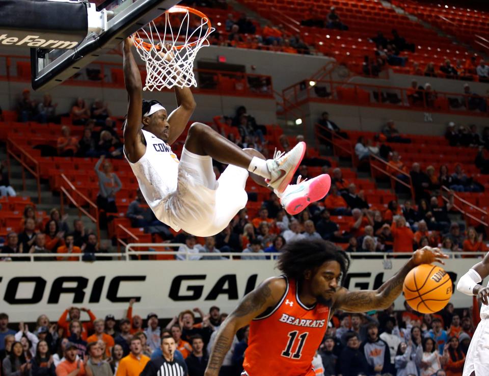 Oklahoma State's Caleb Asberry (5) hangs on to the basket after a dunk next to Sam Houston's Javion May (11) on Tuesday at Gallagher-Iba Arena in Stillwater.