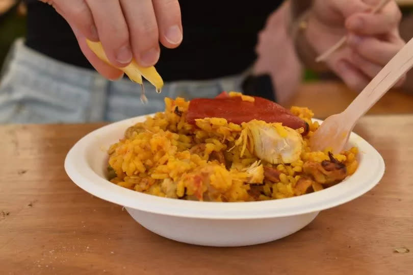 Lemon being squeezed onto paella