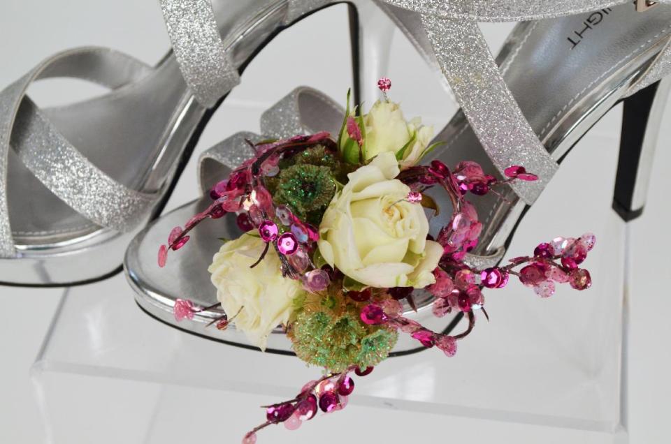 This product image released by Gillespie Florists, Inc. shows a floral decoration for prom shoes. The decoration is made of three white tea roses, three glittered scabiosa pods, pink sequin accents and pink rhinestones. (AP Photo/Gillespie Florists, Inc.)