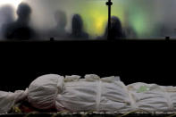 The body of a man who died from COVID-19 is prepared for a burial, at the Behesht-e-Zahra cemetery just outside Tehran, Iran, Wednesday, April 21, 2021. After facing criticism for downplaying the virus last year, authorities have put partial lockdowns and other measures in place to try and slow the coronavirus’ spread, as Iran faces what looks like its worst wave of the coronavirus pandemic yet. (AP Photo/Ebrahim Noroozi)