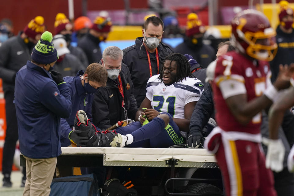 Seattle Seahawks running back DeeJay Dallas (31) reacting to members of the medical team moving him onto a transport cart during the first half of an NFL football game against the Washington Football Team, Sunday, Dec. 20, 2020, in Landover, Md. (AP Photo/Andrew Harnik)