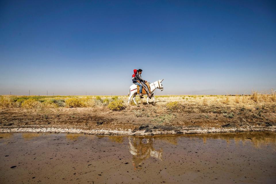 topshot   youths ride together on a donkey past a stream polluted by an oil spill near the village of sukayriyah, in the countryside south of rumaylan rmeilan in syrias kurdish controlled northeastern hasakeh province, on july 19, 2020   oil pollution in syria has become a growing concern since the 2011 onset of a civil war that has taken a toll on oil infrastructure and seen rival powers compete over control of key hydrocarbon fields in the kurdish held northeast, a large storage facility in the rmeilan oil field in hasakeh province is of particular concern, with leaks from the gir zero storage facility have been suspected since at least 2014, and the latest just in march 2020 photo by delil souleiman  afp photo by delil souleimanafp via getty images