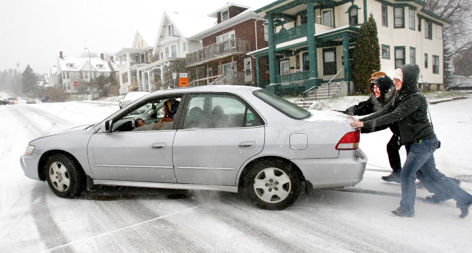 Meghan Dolan steers over an icy road as her husband Zach Oie and two passersby, Davud Schraut and Shannon Dahl, push the car into a parking spot following a snowfall in Duluth, Minnesota November 10, 2014. An arctic blast began to dump heavy snow in parts of the northern Rockies, Plains and the Great Lakes regions on Monday and meteorologists said temperatures are expected to plummet throughout the United States. In Minnesota, police said dozens of car crashes marked the season's first snow as drivers struggled with slippery roads. (REUTERS/Robert King/Duluth News-Tribune)