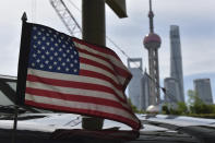 A U.S. flag flies on a U.S. consulate car, with the backdrop of buildings in the Lujiazui financial district, outside a hotel where U.S. trade negotiators are staying, in Shanghai Wednesday, July 31, 2019. (Greg Baker/Pool Photo via AP)