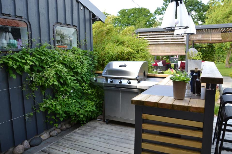 <p>Dark and masculine finishes make this BBQ corner the ideal spot for dad to grill. The lush greenery gives it even more visual appeal.</p>