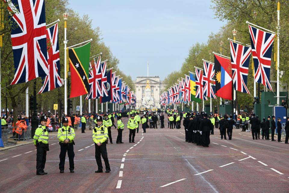 Police officers stand on guard on the route of the 'King's Procession', a two kilometres stretch from Buckingham Palace to Westminster Abbey, as they wait for Britain's King Charles III and Britain's Camilla, Queen Consort to pass in the Diamond State Coach, in central London, on May 6, 2023 ahead of their coronations. - The set-piece coronation is the first in Britain in 70 years, and only the second in history to be televised. Charles will be the 40th reigning monarch to be crowned at the central London church since King William I in 1066. Outside the UK, he is also king of 14 other Commonwealth countries, including Australia, Canada and New Zealand. Camilla, his second wife, will be crowned queen alongside him and be known as Queen Camilla after the ceremony. (Photo by Charles McQuillan / POOL / AFP) (Photo by CHARLES MCQUILLAN/POOL/AFP via Getty Images)