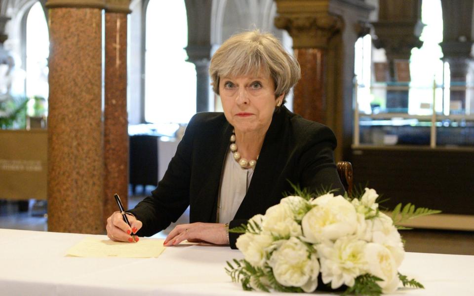 Theresa May writes a message in a book of condolence at Manchester Town Hall - Credit:  BEN BIRCHALL