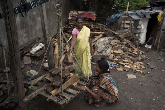An Indian woman weighs wood to sell as fuel, mainly to be used for cooking, at a shop in Gauhati, India, June 9, 2016.