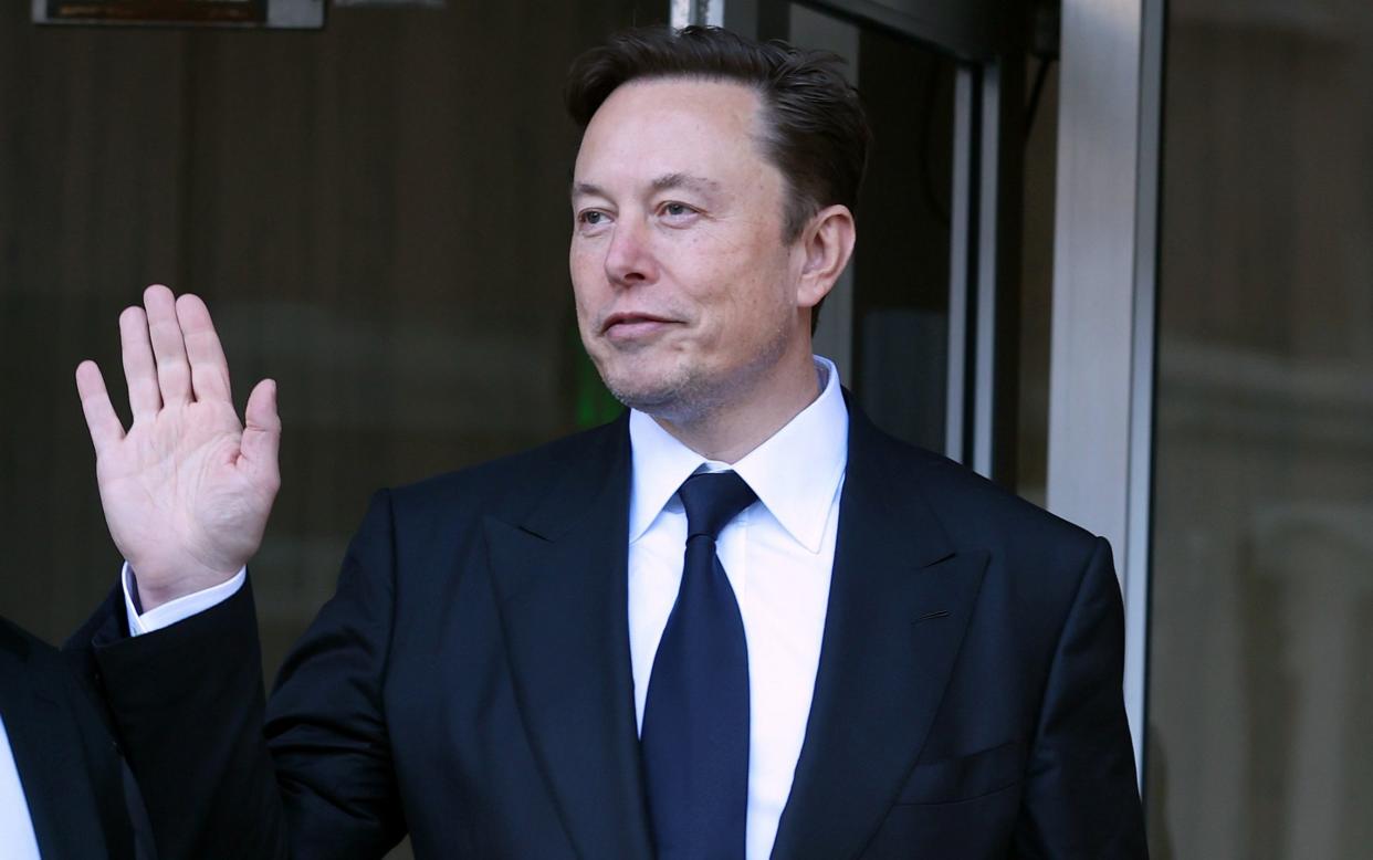 Elon Musk in a dark suit waving - Justin Sullivan/Getty Images