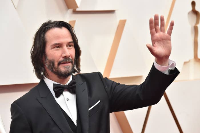 Keanu Reeves waves his hand on the red carpet