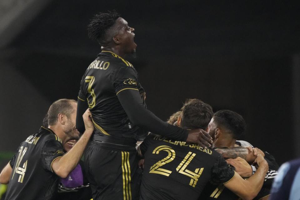 LAFC defender Jesus Murillo rises above teammates hugging.