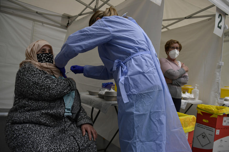 FILE - In this May 13, 2021, file photo, Taia Ilhachamia, a 71 year old Morocco citizen resident in Spain, receives the Pfizer vaccine during a COVID-19 vaccination campaign in Alfaro, northern Spain. Coronavirus infections, hospitalizations and deaths are plummeting across much of Europe. Vaccination rates are accelerating, and with them, the promise of summer vacations. (AP Photo/Alvaro Barrientos)