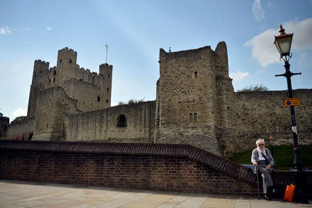 A man sits on a wall in front of Rochester Castle in Rochester, Britain, August 8, 2017. Picture taken August 8, 2017. REUTERS/Hannah McKay