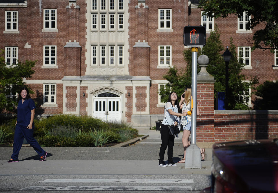 FILE- In this Sept. 18, 2015 file photo, a University of Connecticut student pushes a button at a crosswalk outside one of the student dormitories, in Storrs, Conn. On Friday, Nov. 13, 2020, the University of Connecticut announced that it has placed all dormitories at its main campus under quarantine because of rising coronavirus infections. (AP Photo/Jessica Hill, File)