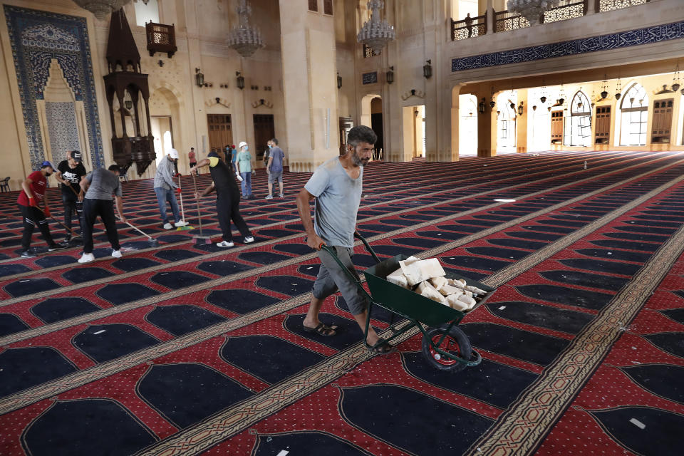 People clean a damaged mosque a day after an explosion hit the seaport of Beirut, Lebanon, Wednesday, Aug. 5, 2020. Residents of Beirut confronted a scene of utter devastation on Wednesday, a day after a massive explosion at the port rippled across the Lebanese capital, killing at least 100 people, wounding thousands and leaving entire city blocks flooded with glass and rubble. (AP Photo/Hussein Malla)