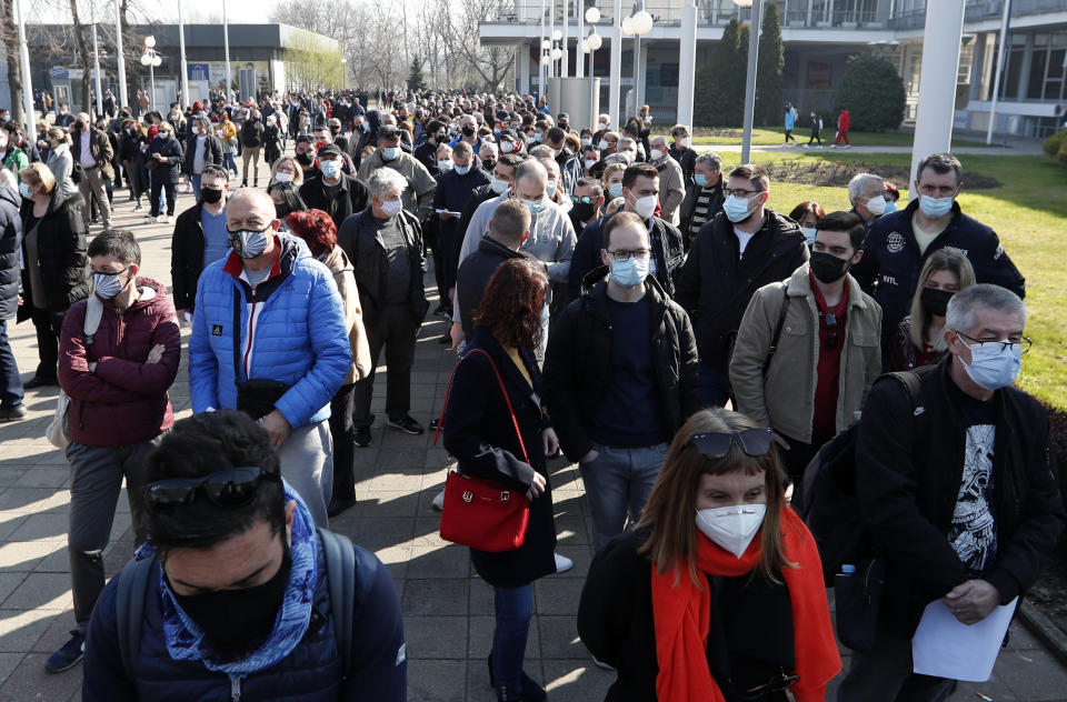 People wait in line to receive a dose of the AstraZeneca vaccine at Belgrade Fair makeshift vaccination center in Belgrade, Serbia, Saturday, March 27, 2021. Thousands of vaccine-seekers from Serbia's neighboring states have flocked to Belgrade after Serbian authorities offered free coronavirus jabs for foreigners if they show up over the weekend. Many arriving with their entire families, long lines of Bosnians, Montenegrins, North Macedonians and even Albanians formed Saturday in front of the main vaccination center in the Serbian capital. (AP Photo/Darko Vojinovic)