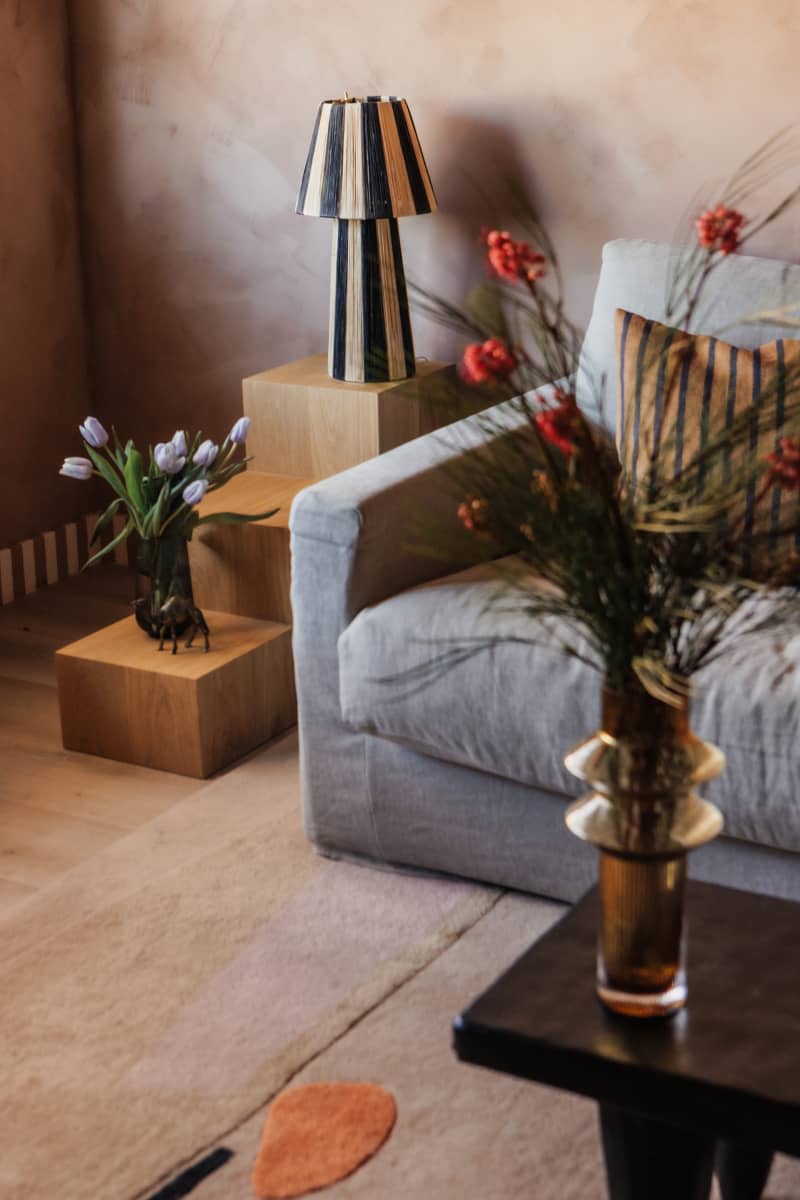 Corner of living room with warm colors, gray sofa, and striped lamp